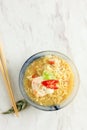 Mie Kuah Telur for Sahur in Ramadan, Instant Noodle Soup Served on Glass Bowl with Poached Egg and Chili
