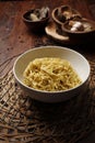 Mie Yamin or Yamin Noodles in a white bowl with a burlap sack mat on Talenanan. Isolated feel of the kitchen table with herbs