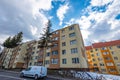 Renewed apartment buildings near road, passing cars.