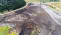 Working Caterpillar and Hitachi excavators in the muddy soil aerial view.