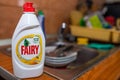 Fairy dishwasher liquid on focus, dirty cutlery and plates on the background.