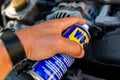 Mechanic using WD-40 multi purpose oil to loosen a tight bolt.