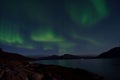 Mighty aurora borealis dancing on night sky over mountain and fjord landscape in late autumn Royalty Free Stock Photo