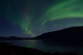 Mighty aurora borealis dancing on night sky over mountain and fjord landscape in late autumn Royalty Free Stock Photo