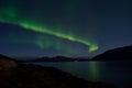 Mighty aurora borealis dancing on night sky over mountain and fjord landscape in late autumn Royalty Free Stock Photo