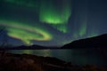 Mighty aurora borealis dancing on night sky over mountain and fjord landscape in late autumn Royalty Free Stock Photo