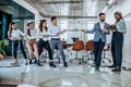 Mighty charismatic boss. Group of young smiling office workers playing tug of war