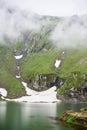 Mighty mountains are covered fog and lake at foot, Romania Royalty Free Stock Photo