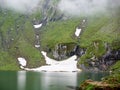 Mighty mountains are covered fog and lake at foot, Romania Royalty Free Stock Photo