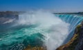 Mighty Niagara River roars over the edge of the horseshoe falls in Niagara Falls Ontario. Misty foggy spray rises up. Royalty Free Stock Photo