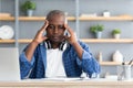 Migraine attack. African american man suffering from headache at workplace while working on laptop Royalty Free Stock Photo