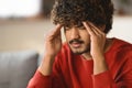 Migraine Concept. Portrait Of Young Indian Man Suffering Acute Headache At Home