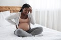 Migraine During Pregnancy. Black pregnant woman suffering from strong headache at home
