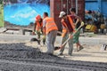 Migrant workers work on the laying of asphalt.