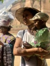 Migun, Myanmar - November 7, 2019: Burmese woman wearing asian conical hat an carrying her child