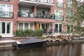 Small boat moored on a river canal outside modern appartment building