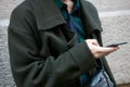 Man with dark green coat and checkered shirt looking at smartphone before Blumarine fashion show, Milan
