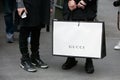 Man poses for photographers holding a big white Gucci shopping bag before Etro and Iceberg fashion show,