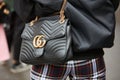 Woman with black leather Gucci bag with golden details and checkered trousers before Fendi fashion show,