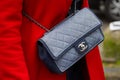 Woman with blue fabric Chanel bag and red coat before Diesel Black Gold fashion show, Milan Fashion Week