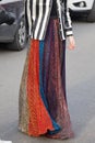 Woman with long skirt in orange, blue and golden colors and black and white striped shirt before Gucci