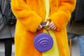 Woman with orange fur coat, yellow dress and purple bag with wifi symbol before Alberta Ferretti fashion show