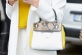 Woman poses for photographers with Coccinelle bag white and yellow before Gucci fashion show, Milan Fashion