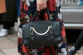 Woman poses for photographers with Coccinelle black leather bag and floral dress before Gucci fashion show,