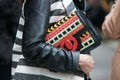 Woman poses for photographers with colorful bag with intricate design before Etro and Iceberg fashion show,