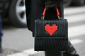 Woman poses for photographers with Les petits joueurs bag with Lego heart before Emporio Armani fashion show Royalty Free Stock Photo