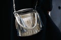 Woman poses for photographers with silver leather bag with fringes before Gucci fashion show, Milan Fashion