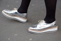 Woman poses for photographers with silver shoes before Tod`s fashion show, Milan Fashion Week Day 3 street