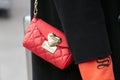 Woman with red and golden Love Moschino bag and black coat before Emporio Armani fashion show, Milan Fashion