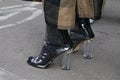 Woman with transparent high heel shoes and brown and black trousers before fashion Albino Teodoro show, Milan