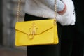 Woman with yellow JW Anderson bag with golden chain and white fur coat before Angelo Marani fashion show,