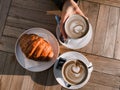 Milan, Italy 03.2024 Cappuccino and croissant on the table in the cafe. Delicious breakfast. Womens hands hold a cup of Royalty Free Stock Photo