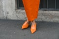 Elegant woman wearing orange long dress, black bag and white gloves