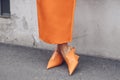 Elegant woman wearing orange long dress, black bag and white gloves