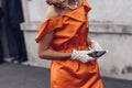 Elegant woman wearing orange long dress, black bag and white gloves