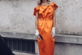 Elegant woman wearing orange long dress, black bag and white gloves