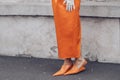 Elegant woman wearing orange long dress, black bag and white gloves