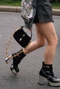 Milan, Italy - February 24, 2023: fashioner wearing shoulder bag and metallic platform boots from Gucci. Fashion blogger