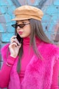 Model wears a fuchsia turtleneck sweater, a fuchsia jacket and a hat