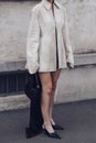 Street style, woman wearing cream leather jacket, mini skirt with long train, black Prada bag and Prada heels