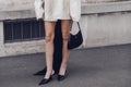 Street style, woman wearing cream leather jacket, mini skirt with long train, black Prada bag and Prada heels