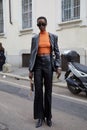 Top model with black leather jacket and trousers and orange turtleneck before Genny fashion show