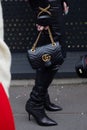 MILAN, ITALY - FEBRUARY 24, 2023: Woman with black Gucci leather bag with golden chain before Gucci fashion show, Milan Fashion