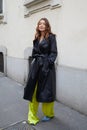 MILAN, ITALY - FEBRUARY 23, 2023: Woman with black leather trench coat and yellow trousers before Genny fashion show, Milan