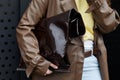 MILAN, ITALY - FEBRUARY 24, 2023: Woman with brown leather trench coat and Jil Sander bag before Gucci fashion show, Milan Fashion