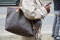 MILAN, ITALY - FEBRUARY 22, 2023: Woman with brown Louis Vuitton bag and beige trench coat before Fendi fashion show, Milan